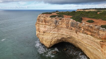 Rocky coastal cliff with natural arch in Faro, Algarve, Portugal