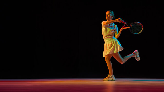 Female tennis player hitting backhand shot with power and determination. Concept of athletic performance, sports science, discipline training, and motivational fitness education. - Powered by Adobe