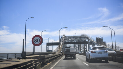 Traffic on Auckland harbour bridge. 80km per hour speed limit sign on the road. Auckland. New Zealand.
