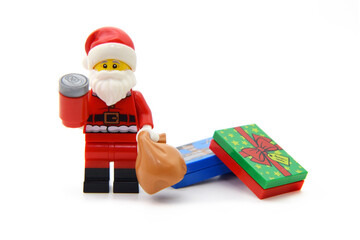 Naklejka premium Editorial illustrative image of lego minifigure of Santa Claus with red Cola cans and present boxes isolated on white.