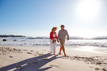 Couple, walk and holding hands on trip, beach or romance on getaway, mockup space and people on date. Outdoor, mature man and bonding with woman on holiday, marriage and anniversary in nature and sea