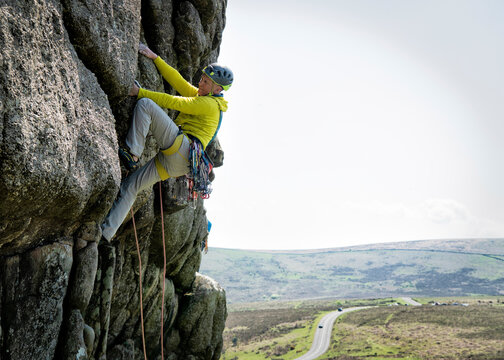 Rock climber scaling Haytor Low Man in Dartmoor England with safety gear