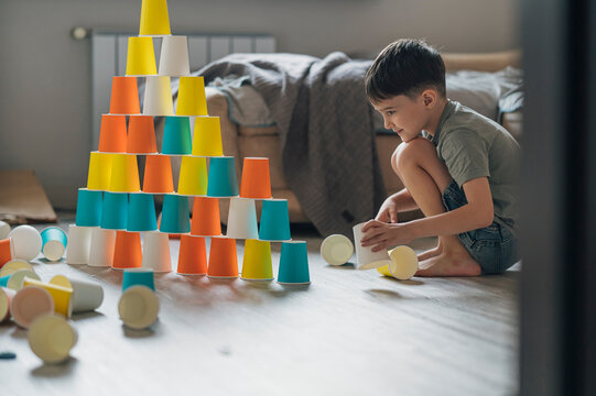Child building a colorful paper cup pyramid during play indoors