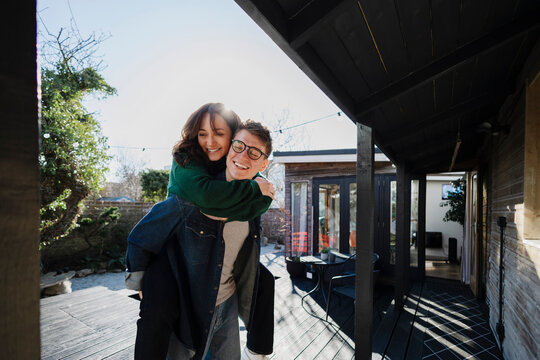 Couple enjoying a playful piggyback ride in their backyard patio