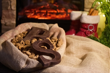 Fototapeta premium Warm Holiday Hearth. Cozy scene with chocolate letters, burlap sack, and holiday decor by the fireplace.