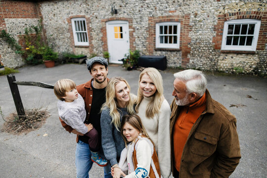 Family portrait with grandparent outdoors at country house in autumn