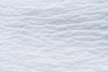 Smooth snow surface forms soft wavy texture creating calm winter background ideal for seasonal designs and minimalistic visual concepts