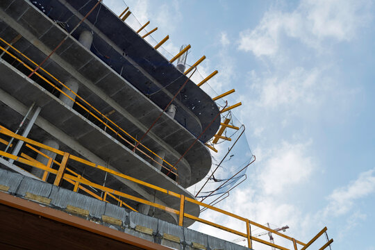 Curved concrete floors of rising building frame stand against bright sky, highlighting structure growth and modern urban development stage.