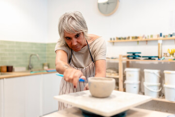 Smiling woman creating pottery in ceramic art workshop