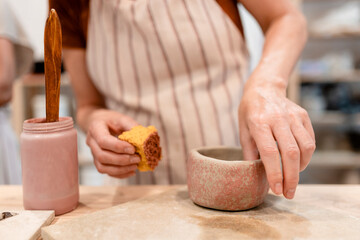 Smiling artisan shaping ceramic bowl in pottery workshop