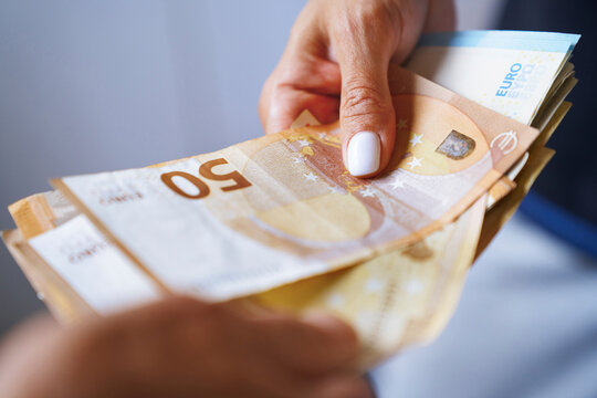 Hand giving and receiving euro banknotes in financial transaction