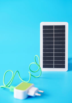 Solar panel and electric plug on blue background symbolizing renewable energy