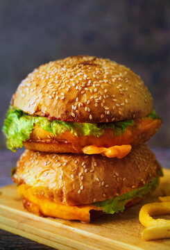 Double cheeseburger with lettuce and fries on wooden board