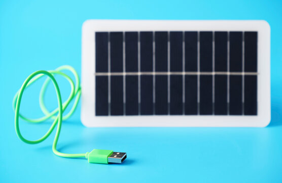 Green USB cable and solar panel representing renewable energy