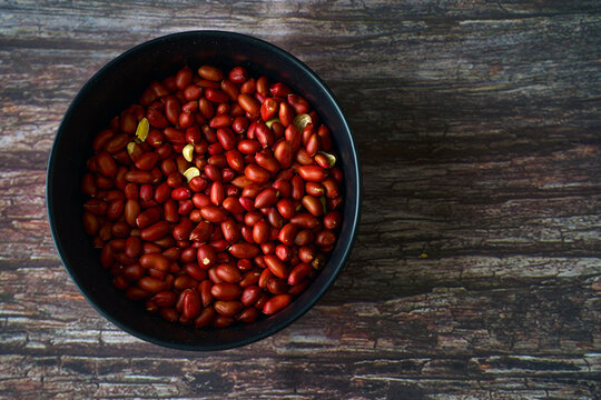 Bowl of organic peanuts on rustic table viewed from above