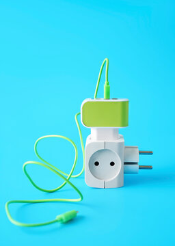 Green and white plug adapter with cable on blue background