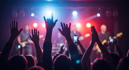 Fototapeta premium Many people are actively raising their hands at a live music concert. Audience enjoying a rock band performance with festive stage lights. Party event or festival concept.