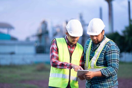 Two engineers reviewing project data on tablet at construction site, symbolizing modern teamwork and digital transformation in industry.