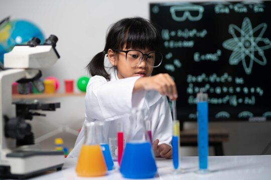 Two girls in science class exploring experiments with microscope and chemical beakers, highlighting curiosity and learning in STEM education.
