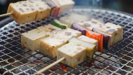 Grilled tofu and vegetables on skewers over a BBQ grill, outdoor cooking scene with smoke. Potential use food blog