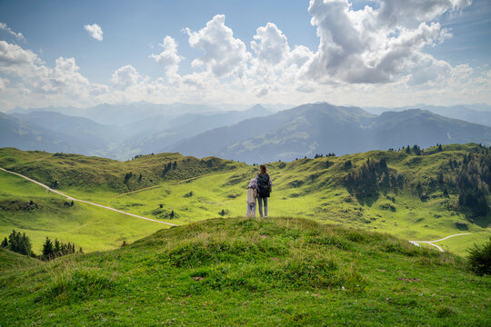 Mother and daughter looking at view under cloudy sky