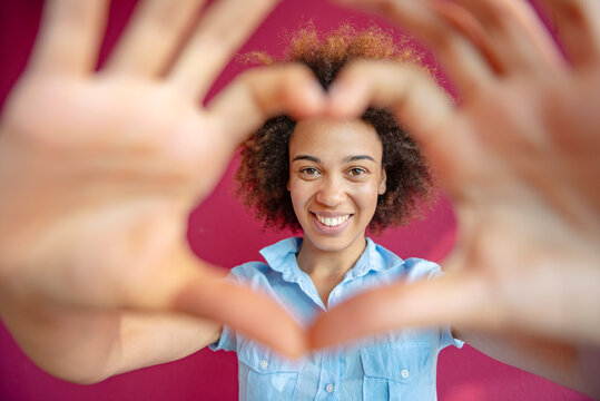 Smiling employee making heart shape with hands in office portrait