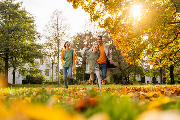Family running together in autumn park on a sunny day