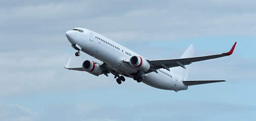 Airplane take off on the blue sky, with white clouds. Aircraft flying on sky background. White...