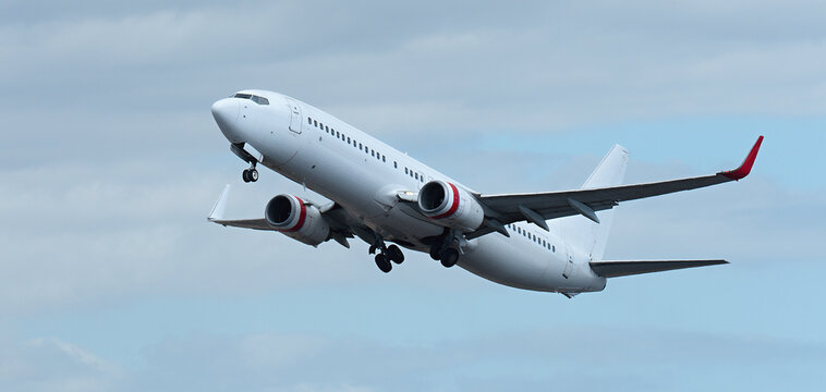 Fototapeta Airplane take off on the blue sky, with white clouds. Aircraft flying on sky background. White passenger jet plane in the blue sky. Low angle view of Airplane flying under blue sky, with white clouds