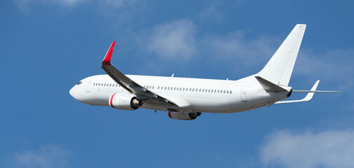 Airplane take off on the blue sky, with white clouds. Aircraft flying on sky background. White passenger jet plane in the blue sky. Low angle view of Airplane flying under blue sky, with white clouds