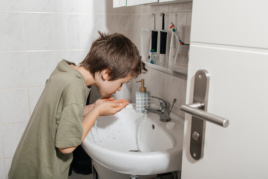 Boy washing face at bathroom sink practicing morning hygiene routine