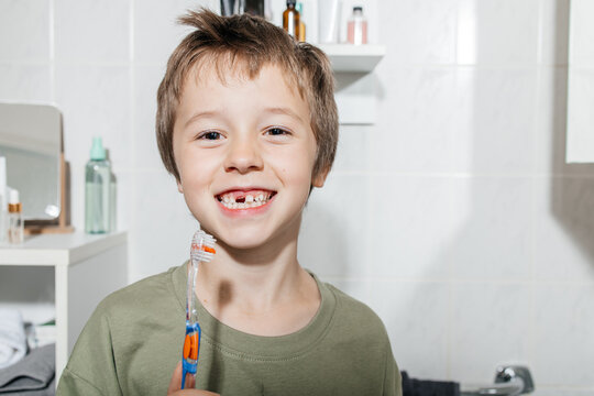 Smiling boy holding toothbrush in bathroom during morning routine - Powered by Adobe