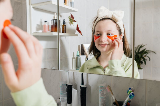 Teenager applying eye patches as part of morning skincare routine
