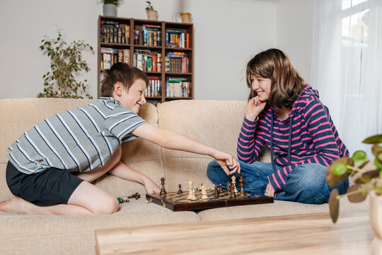 Friends playing chess and enjoying strategy game on sofa at home