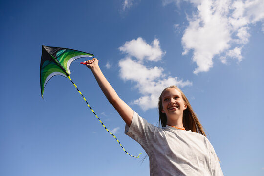 Smiling child flying a kite outdoors on a sunny day