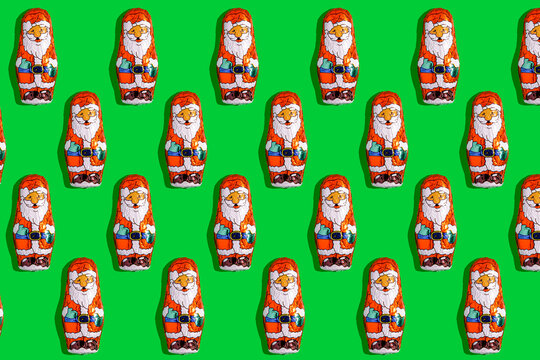 Santa Claus mini chocolates arranged in festive pattern on green background