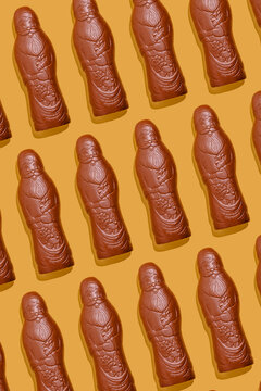 Chocolate Santa Claus candies in seamless pattern on orange background