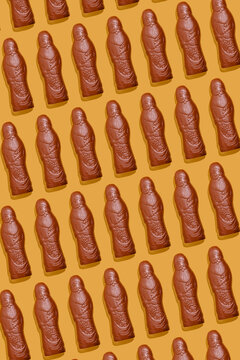 Chocolate Santa Claus candies arranged in pattern on orange background