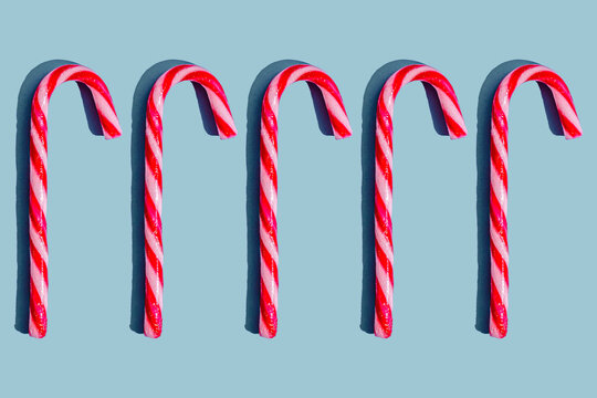 Striped candy canes arranged in a row on a blue background