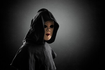 Scary lady with hooded cloak in the dark
