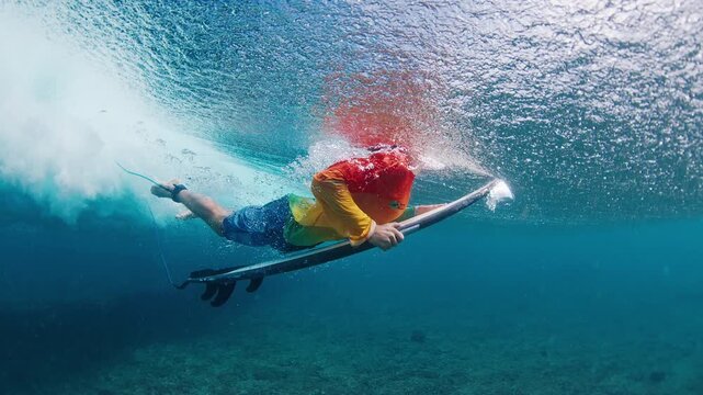 Surfer under the wave. Underwater view of the teen boy surfer diving under the wave with surf board