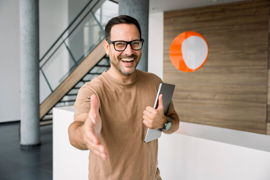 Confident business person smiling and offering handshake in office