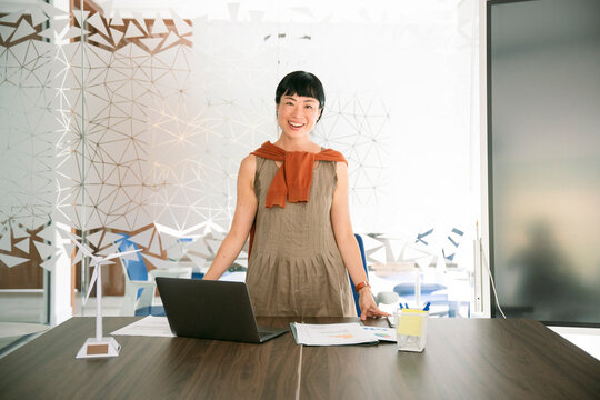 Confident businesswoman standing at office desk smiling at camera