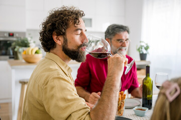 Family enjoying lunch and wine together at home around dining table
