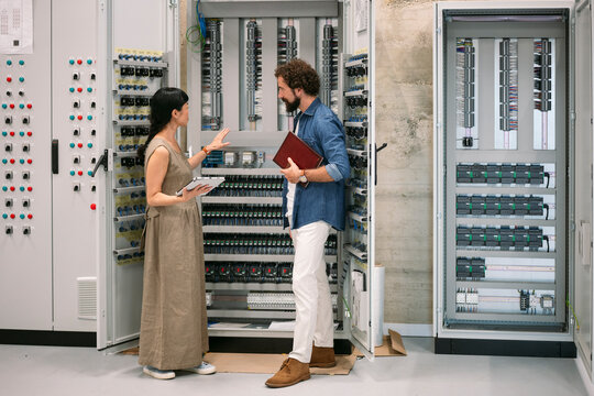 Engineer and technician discussing energy innovation in control room