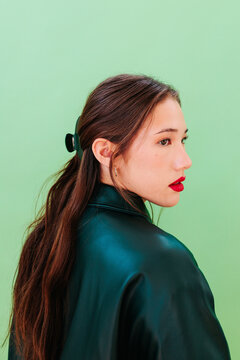 Side portrait with dark green jacket on green background in studio