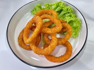 Crispy golden onion rings served on a plate with fresh lettuce, perfect as a snack or appetizer.
