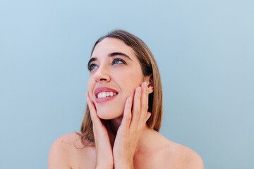 Happy woman with natural skin tone looking up in a beauty portrait