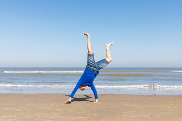 Man doing cartwheel on sunny beach expressing joy and freedom