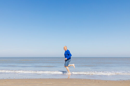 Man running along the beach at the North Sea embracing positivity